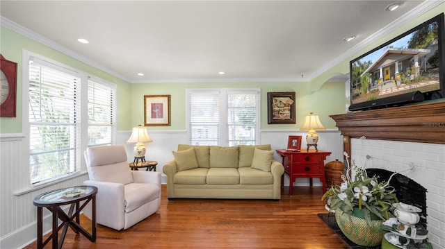 living room featuring hardwood / wood-style flooring, crown molding, a brick fireplace, and a wealth of natural light