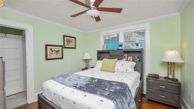 bedroom featuring dark wood-type flooring, ornamental molding, and ceiling fan