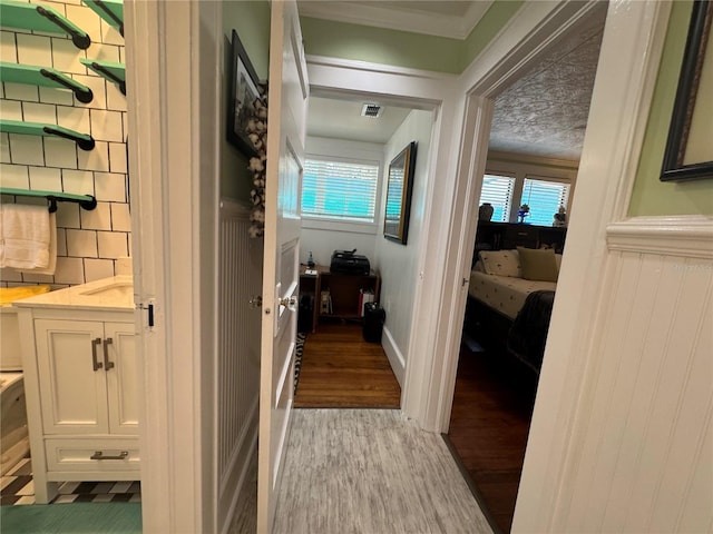 corridor with crown molding and light hardwood / wood-style flooring