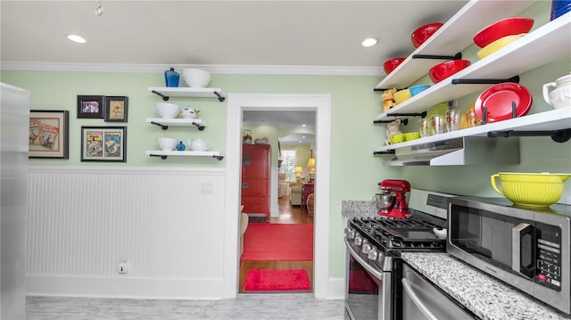 kitchen with stainless steel appliances, ornamental molding, exhaust hood, and light hardwood / wood-style flooring