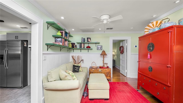 sitting room featuring ceiling fan, ornamental molding, and wood-type flooring