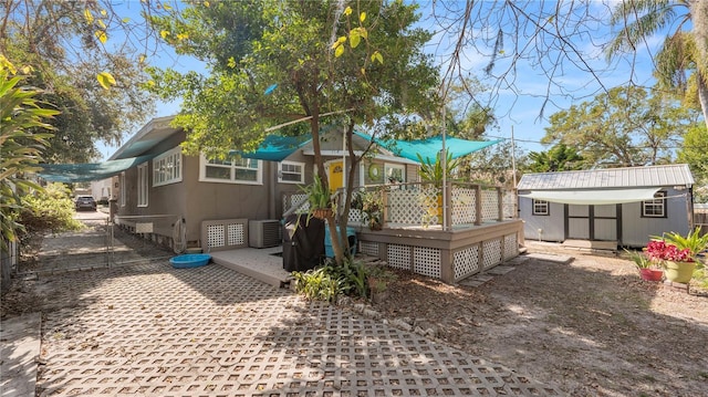 rear view of house featuring a wooden deck, central air condition unit, and a storage unit