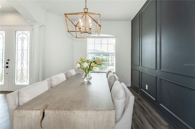 dining space featuring french doors, an inviting chandelier, dark wood-type flooring, and ornate columns