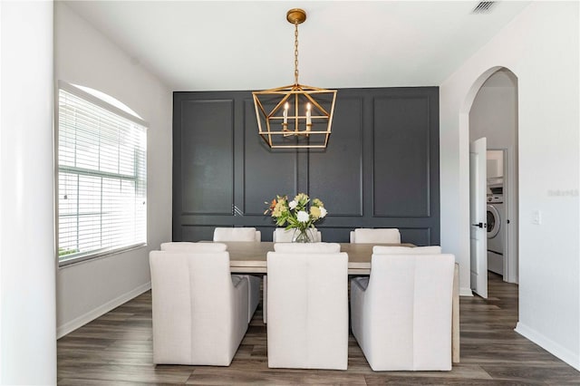 dining area featuring washer / dryer, dark wood-type flooring, and a chandelier