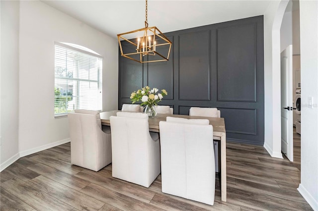 dining room featuring hardwood / wood-style flooring, washer / clothes dryer, and an inviting chandelier