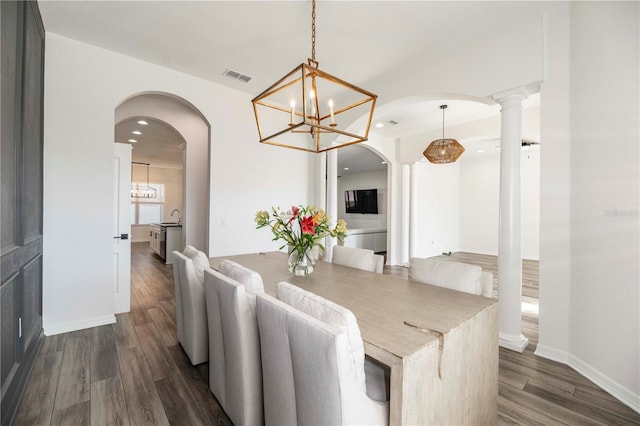 dining area featuring decorative columns, dark wood-type flooring, and sink