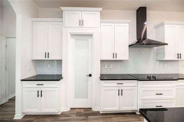 kitchen featuring black electric cooktop, wall chimney range hood, dark hardwood / wood-style floors, and white cabinets