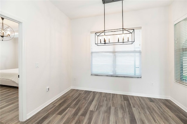 unfurnished dining area with dark wood-type flooring and a chandelier