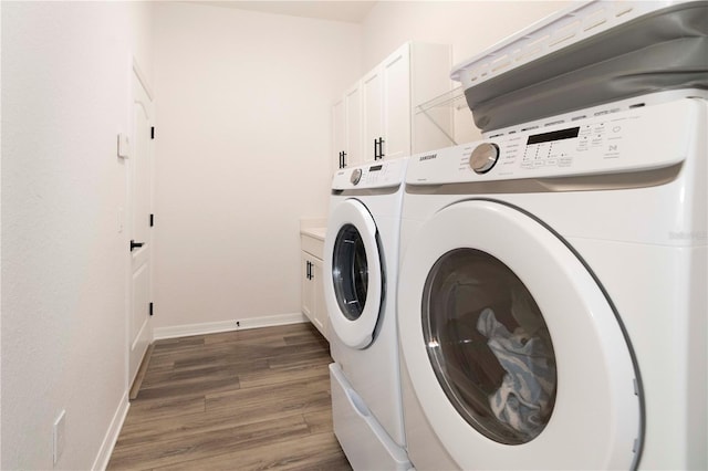 washroom featuring separate washer and dryer, dark wood-type flooring, and cabinets