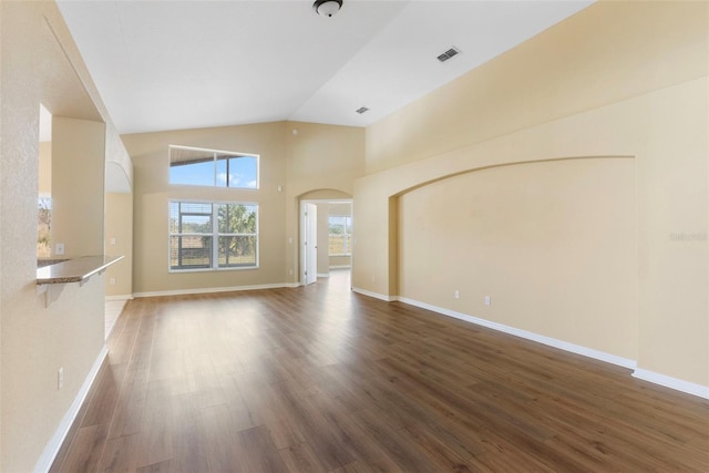 unfurnished living room with dark wood-type flooring and high vaulted ceiling