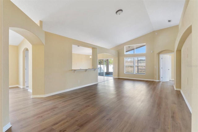 unfurnished living room with wood-type flooring and high vaulted ceiling