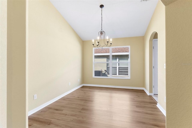 unfurnished dining area with vaulted ceiling, a chandelier, and light wood-type flooring