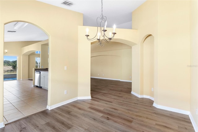 unfurnished dining area featuring a towering ceiling, hardwood / wood-style floors, and a notable chandelier