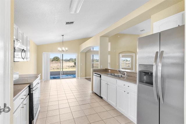 kitchen with light tile patterned flooring, appliances with stainless steel finishes, white cabinetry, lofted ceiling, and sink