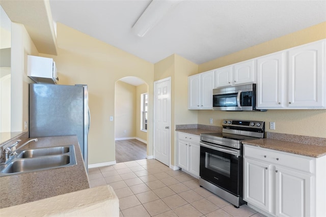 kitchen featuring sink, light tile patterned floors, stainless steel appliances, and white cabinets