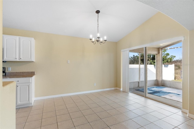 unfurnished dining area with a notable chandelier, lofted ceiling, and light tile patterned floors