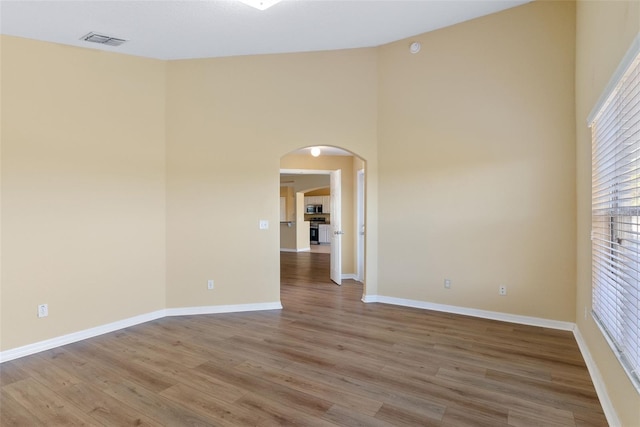 empty room featuring a high ceiling and wood-type flooring