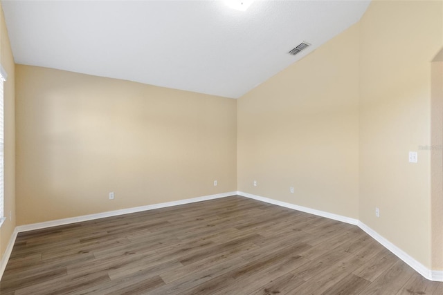 spare room with wood-type flooring and vaulted ceiling