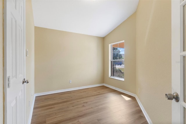 spare room featuring vaulted ceiling and light hardwood / wood-style floors