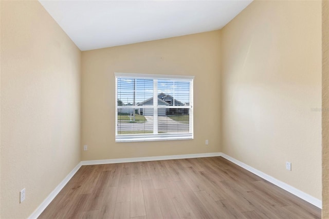 empty room featuring vaulted ceiling and light wood-type flooring