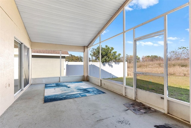 unfurnished sunroom featuring vaulted ceiling and a healthy amount of sunlight