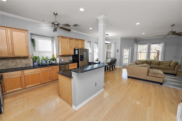 kitchen with light wood-type flooring, a kitchen island, ceiling fan, stainless steel appliances, and backsplash