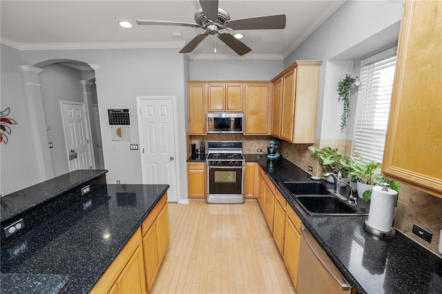 kitchen featuring sink, dark stone countertops, dishwashing machine, gas range oven, and decorative columns