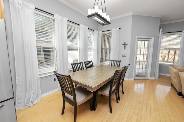 dining area featuring a notable chandelier, ornamental molding, and light wood-type flooring