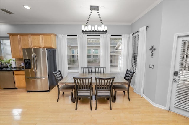 dining space featuring crown molding, an inviting chandelier, and light wood-type flooring