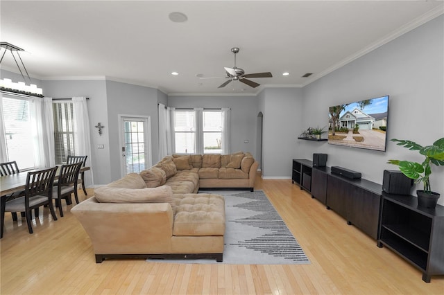 living room with ornamental molding, ceiling fan with notable chandelier, and light hardwood / wood-style flooring