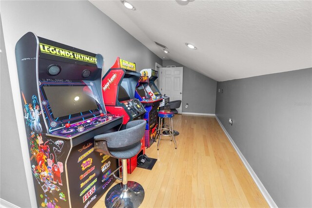 game room featuring a textured ceiling, vaulted ceiling, and wood-type flooring