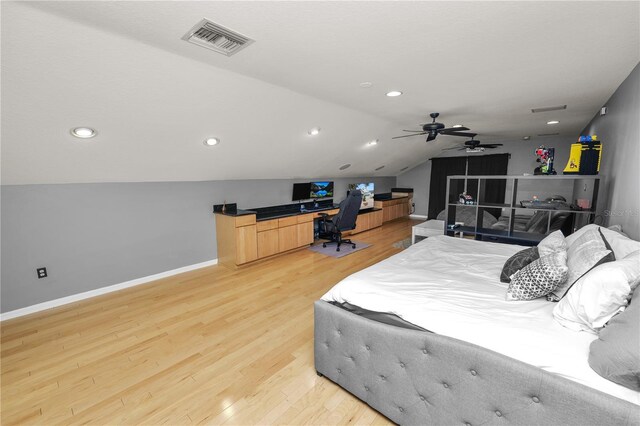 bedroom with lofted ceiling, built in desk, and light wood-type flooring