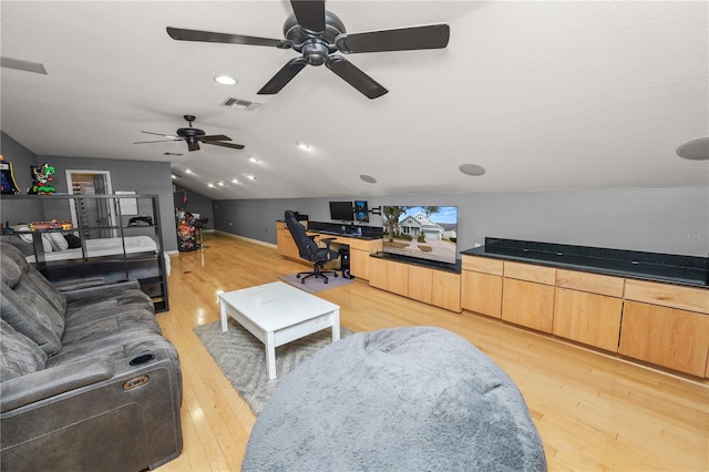 living room featuring lofted ceiling, built in desk, and light wood-type flooring