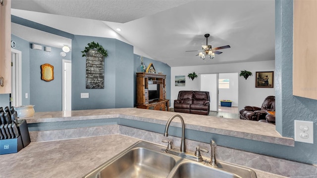 kitchen featuring lofted ceiling, sink, a textured ceiling, and ceiling fan