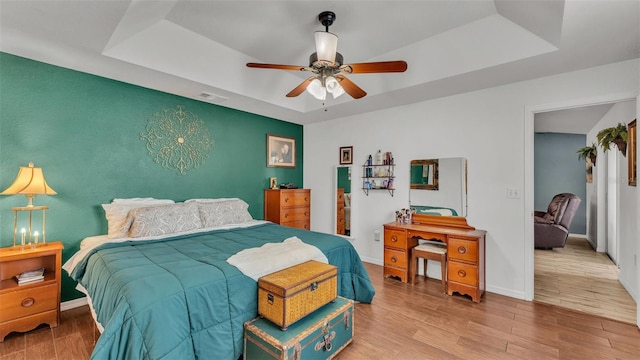 bedroom featuring hardwood / wood-style floors, a tray ceiling, and ceiling fan