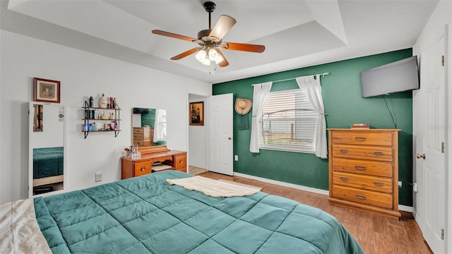 bedroom featuring a tray ceiling, light hardwood / wood-style flooring, and ceiling fan