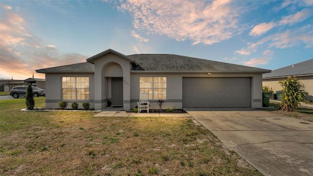 ranch-style house with a garage and a yard