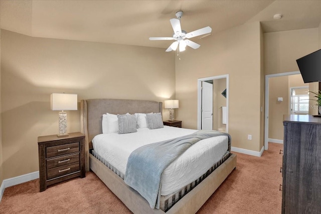 bedroom with ceiling fan, light colored carpet, ensuite bathroom, and vaulted ceiling