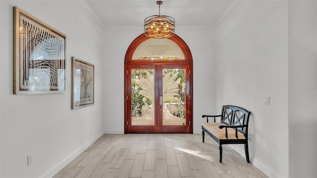 interior space featuring a notable chandelier, crown molding, light hardwood / wood-style floors, and french doors