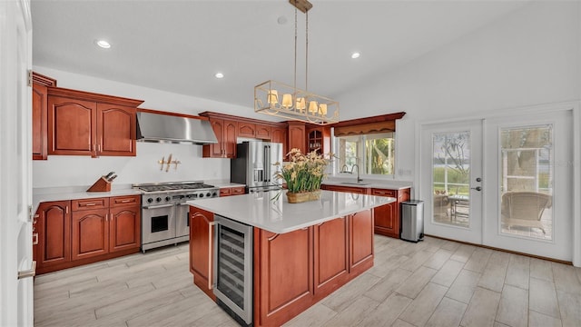 kitchen featuring decorative light fixtures, wine cooler, a center island, stainless steel appliances, and wall chimney exhaust hood