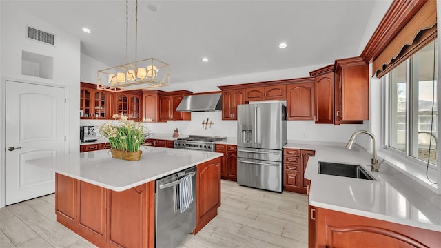 kitchen featuring a kitchen island, sink, hanging light fixtures, stainless steel appliances, and wall chimney exhaust hood