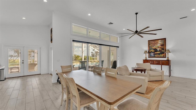 dining space with french doors, a towering ceiling, ceiling fan, and light hardwood / wood-style floors