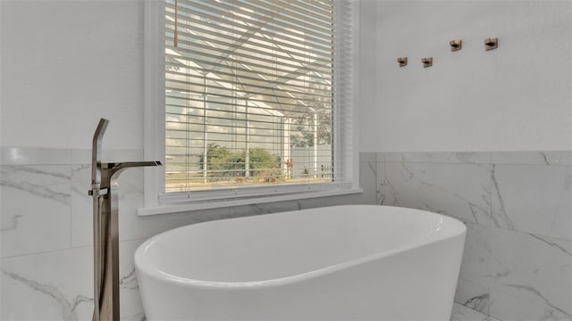 bathroom with a tub to relax in and tile walls