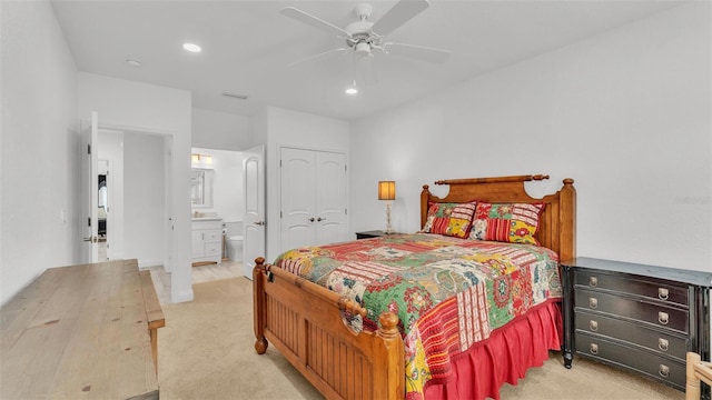 bedroom with ceiling fan, light colored carpet, ensuite bathroom, and a closet