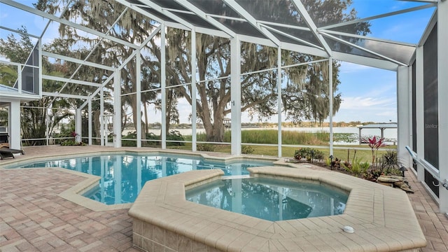 view of pool featuring a patio, glass enclosure, and an in ground hot tub