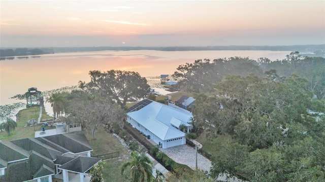 aerial view at dusk featuring a water view