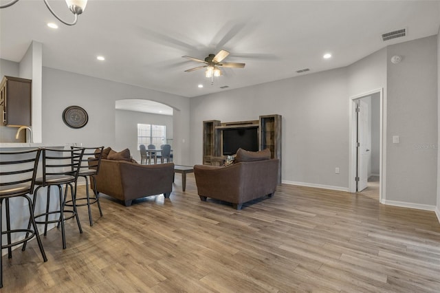 living room with sink, ceiling fan, and light hardwood / wood-style flooring