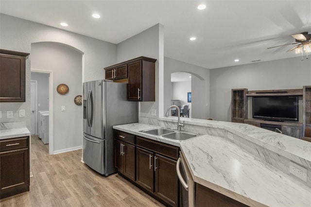 kitchen featuring sink, ceiling fan, appliances with stainless steel finishes, washer and dryer, and light wood-type flooring