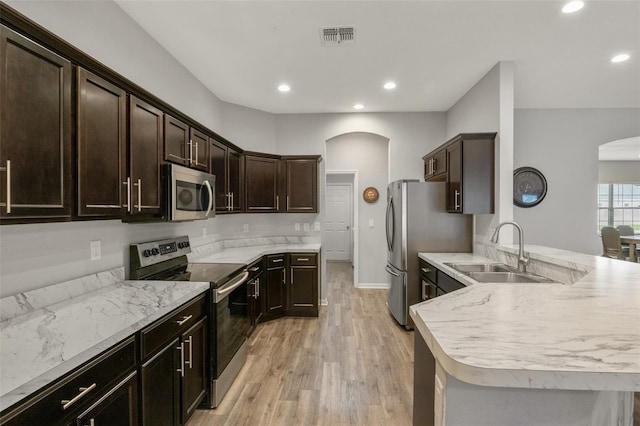 kitchen with sink, light hardwood / wood-style flooring, stainless steel appliances, dark brown cabinetry, and kitchen peninsula