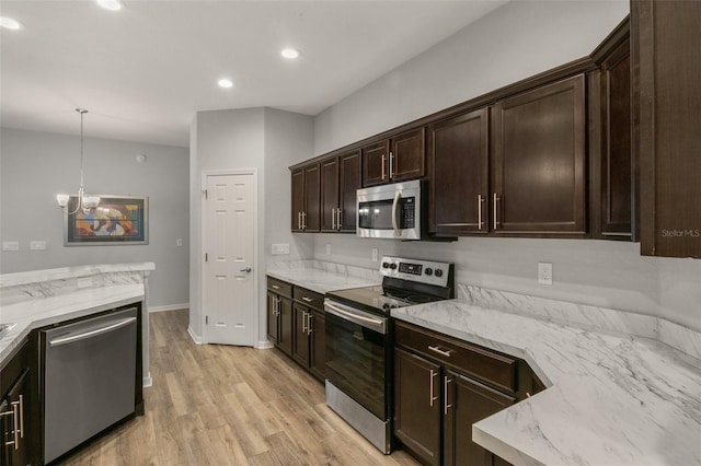 kitchen featuring appliances with stainless steel finishes, pendant lighting, light hardwood / wood-style floors, light stone countertops, and dark brown cabinets